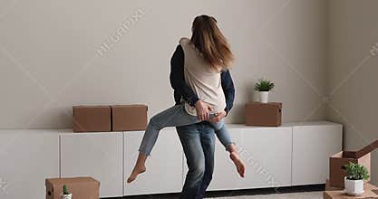Husband lift wife on arms swirling celebrate relocation day