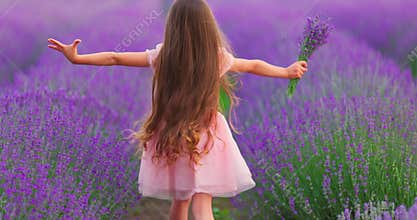 Happy little girl with dress enjoying lavender field with bouquet of flowers