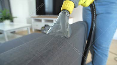 Furniture wet cleaning concept. A woman cleaning a sofa with a carpet extractor