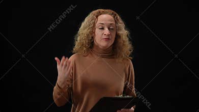 Emotional Caucasian woman talking gesturing standing at black background. Portrait of agitated female speaker presenting