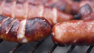 Brats being cooked on a grill with flame and smoke