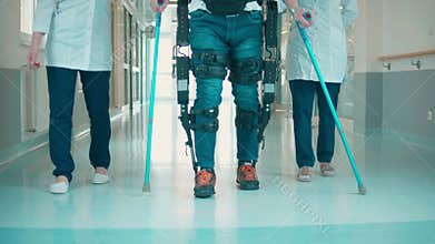 Hospital hall with a man walking in the exoskeleton with assistance