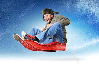 Cool young man fly on a sled in the snow