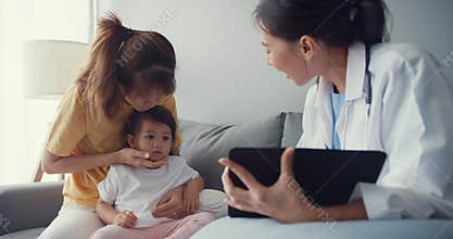 Young Asia female pediatrician doctor and little girl patient using digital tablet sharing good health test news with happy mom