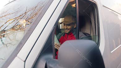 Delivery guy wearing a cap sitting in the front seat of the van - parcel delivery