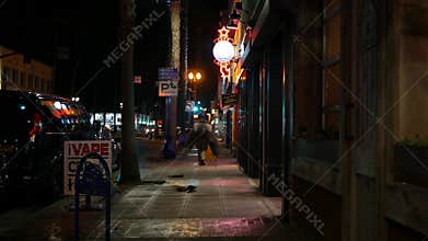 Man look like homeless walking, city street walkway at night. Male person on sidewalk California USA