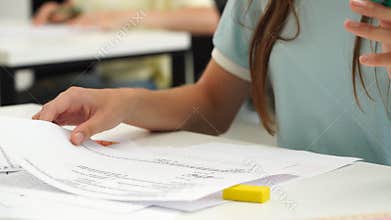 High school teenagers in classroom, close up shot girl writing math exam, solving task on paper sheet. Modern education