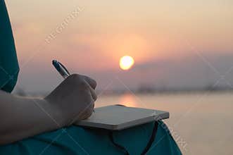 Woman writing in her diary at sunset