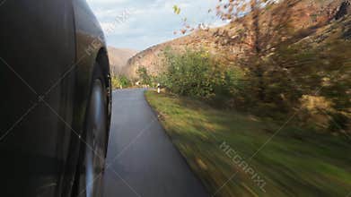 Close up black car Front Right Wheel Of A Car Driving On The Road POV in beautiful early morning in Armenia curvy countryside road