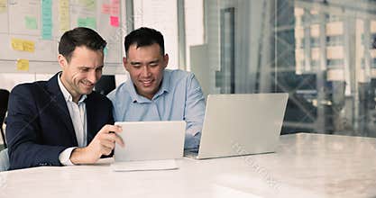 Two multiethnic workmates review agenda, presentation, relevant documents on tablet