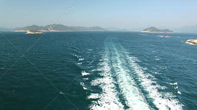 A ferry leaving a trail of white water as it travels past islands in the sea. Aerieal view. 4K