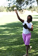 Young African American Woman Throwing baseball Park