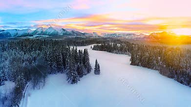 Winter colors. Snowcapped mountains and colorful sunset, aerial winter landscape.