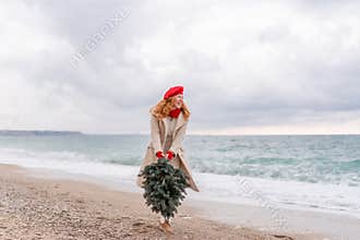 Redhead woman Christmas tree sea. Christmas portrait of a happy redhead woman walking along the beach and holding a