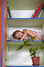 Smiling little girl reading a book in a bookcase