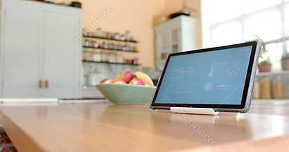 Close up of tablet with smart home on screen over fruit in bowl in kitchen, slow motion