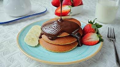 Liquid dark chocolate sauce is poured on buttermilk pancakes.