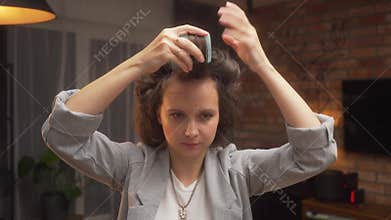 The woman explains and shows how to do her hair and wind bangs on curlers.