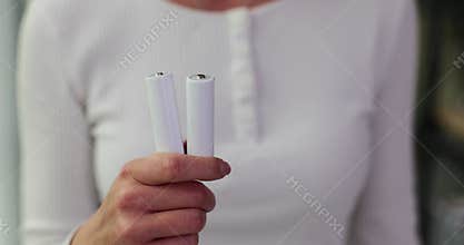 Woman hand holds white AA batteries
