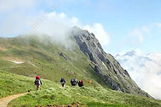 Tourist team hiking on trail in mountains