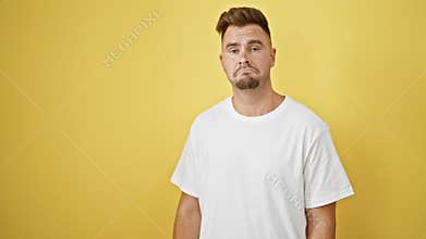 Hispanic man with beard posing confused against yellow wall