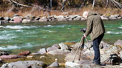 Video of a videographer filming with a camcorder Altai mountain river