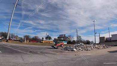 Bobcats dumping rocks in a pile in a parking lot of a new Harbor Freight tools
