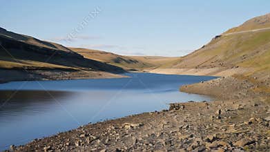 A reservoir at its lowest level in years revealing the highwater marks of better times on its rocky banks