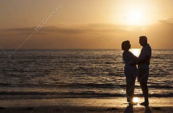 Happy Senior Couple Embracing on Sunset Beach