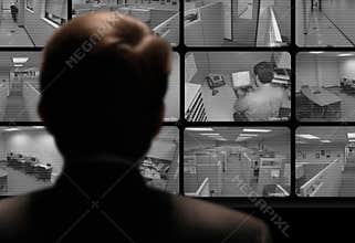Man watching employee work via closed-circuit video monitor