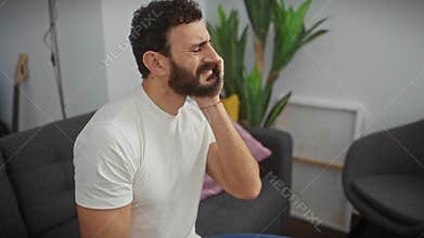 Handsome middle-aged man in pain, touching aching tooth at home, showing painful expression due to dental illness