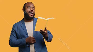 Joyful person having fun, being amused by literature novel, studio background
