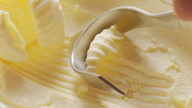 Butter is scraped off with a special butter knife from a pack of butter.
