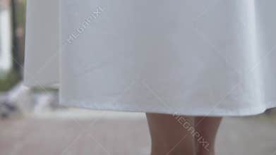 Closeup of white shoes on human feet on gray asphalt