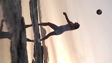 Vertical video. Beautiful woman playing volleyball at sunset by the sea.
