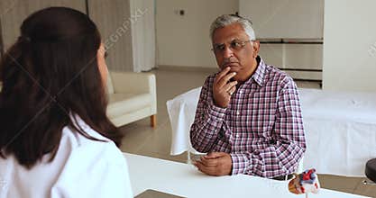 Old Indian man visiting cardiologist office, talking to younger doctor