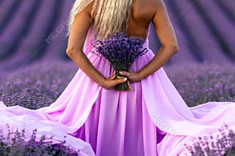 Back view woman lavender sunset. Happy woman in pink dress holds lavender bouquet. Aromatherapy concept, lavender oil