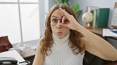 Shocked office beauty! young woman, working, pulls off surprised look with \'ok\' gesture, looking through fingers. face full of