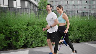 A young positive sportive family in the morning jog with pet, a Jack Russell Terrier dog, outdoors in the city park