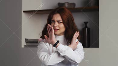 Portrait displeased woman gesturing stop sign with hands at home . Closeup young model saying no on office background