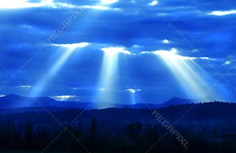 Light rays from heaven shooting down over valley