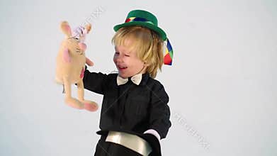Little boy magician shows focus with rabbit in