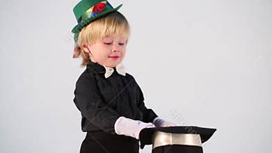 Little boy in magician suit with wand and green