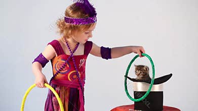 Little girl in costume magician training kitten
