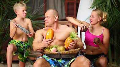 Family of three on a sandy beach near bungalow