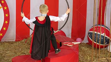 Little boy in black suit and red cloak sits