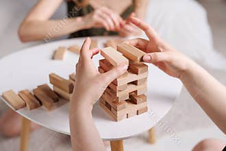 two women playing Jenga board game at home, excitement and relaxation, mind development concept,