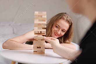 two women playing Jenga board game at home, excitement and relaxation, mind development concept,