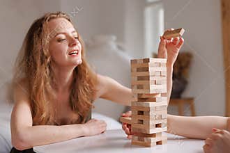 two women playing Jenga board game at home, excitement and relaxation, mind development concept,
