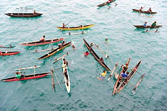 People having fun in canoes on Pacific Ocean near Wewak, Papua New Guinea. Water battle in the summer rain.